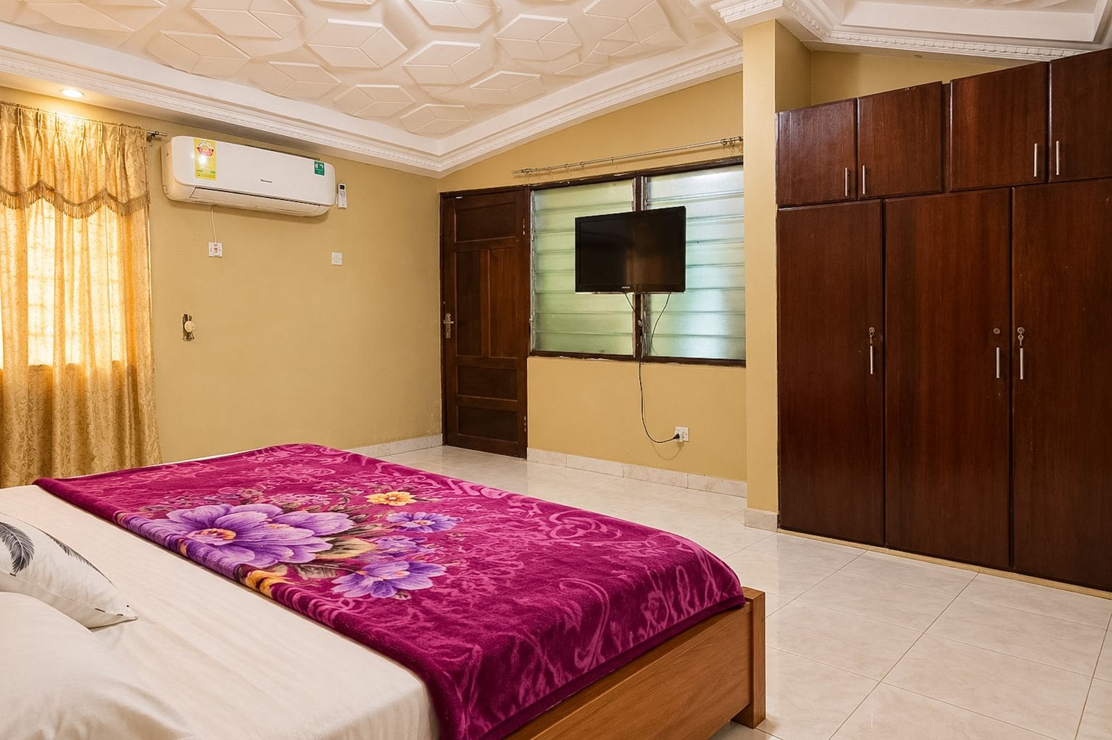 Bedroom with a large bed, fitted wardrobes, TV and air conditioning